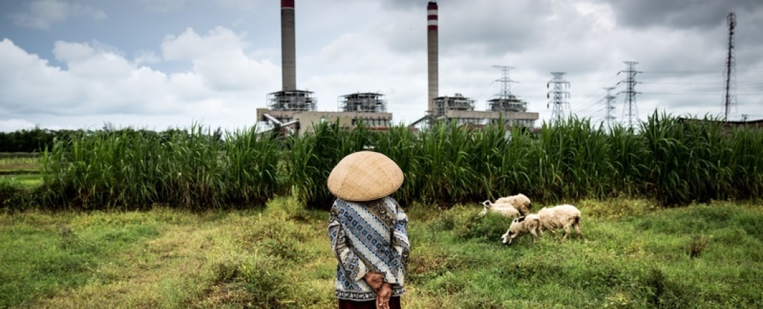picture of an Indonesian farmer looking at a coal plant